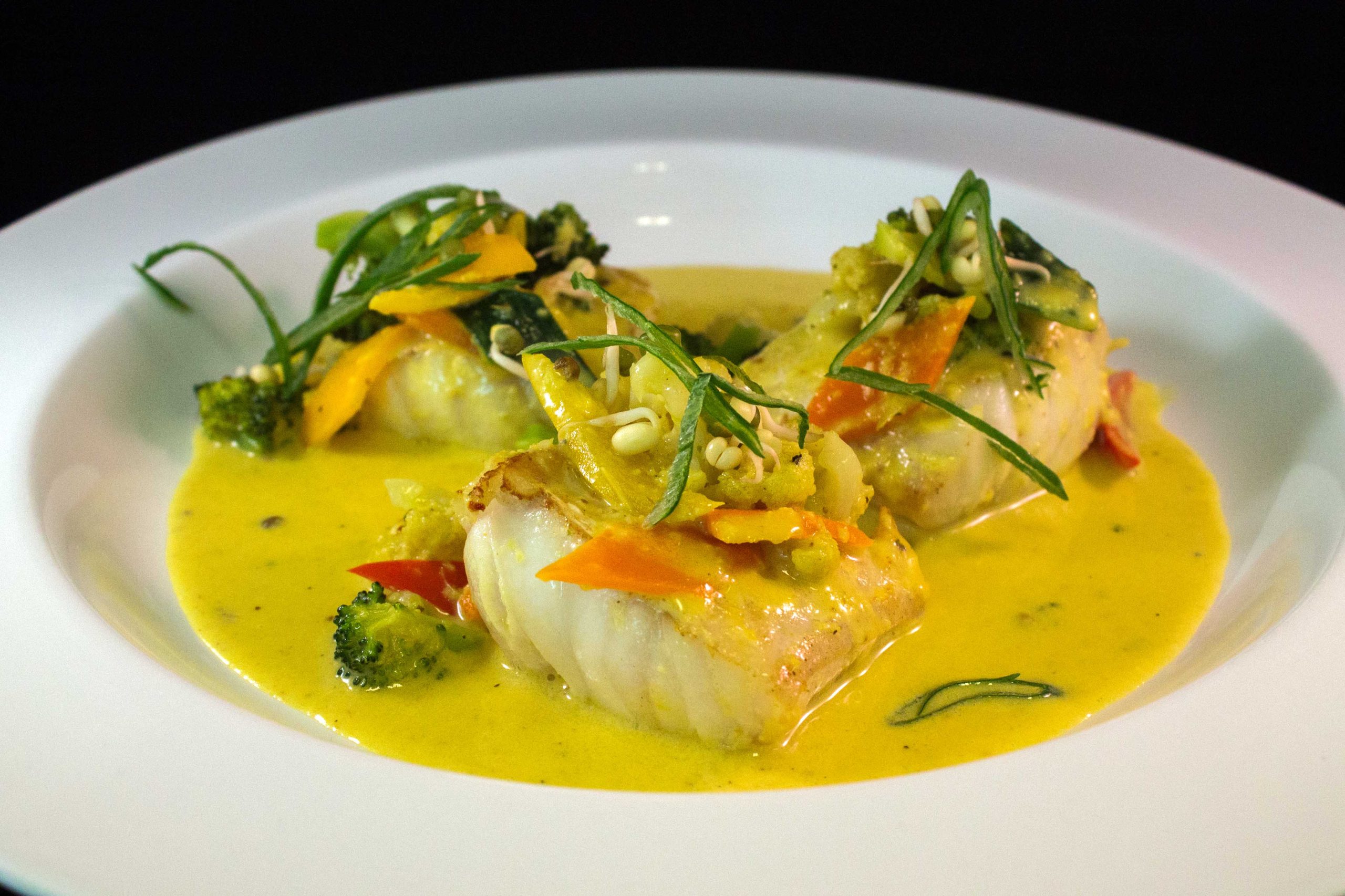 Un plato con una preparación de congrio al curry