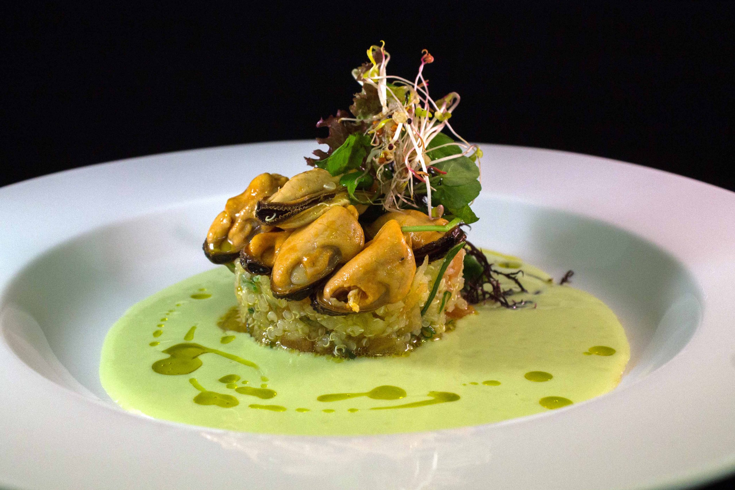 Plato con una porción de choritos sobre un ceviche de quinoa
